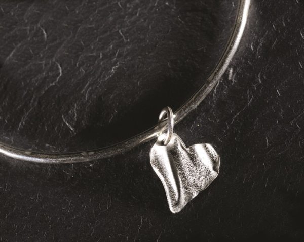 A tiny silver ribbon heart on a slim bangle, designed and created by Silverfish Designs