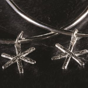 A slim silver bangle with a delicate snowflake drop. Designed and handmade by Carol James of Silverfish Designs