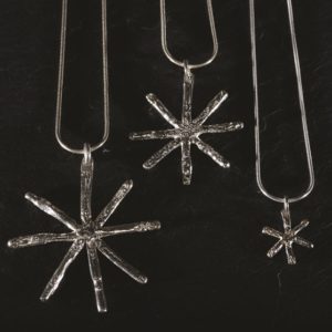 Tiny, medium and large silver snowflake pendants hung on silver snake chains. Designed and handmade by Carol James of Silverfish Designs